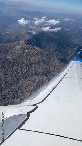 Airplane window view of majestic mountains and plane wing