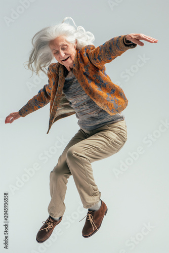 An elderly woman is jumping on a white background