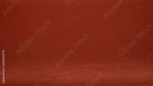 Smooth orange liquid texture drifting in abstract macro slow motion background, swirl and spin in gelatinous goo
