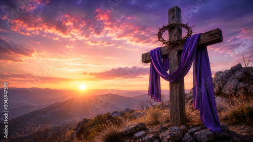 Wooden cross silhouette against dramatic sunset sky over misty mountain landscape