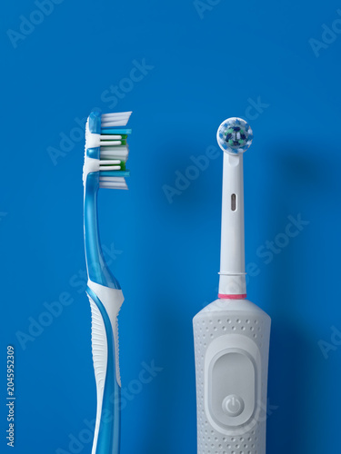 Photography Close-up of electric toothbrush and manual toothbrush on blue background