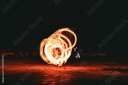 Obraz na plátně Fire spinning performance with glowing circular flame trails at night