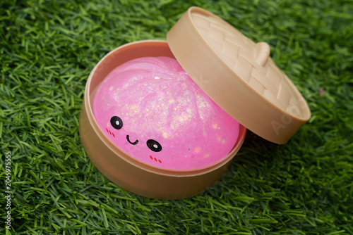 Photos Cute pink glitter dumpling squishy in a small box placed on vibrant green grass,