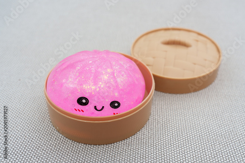 Sparkling pink squishy dumpling toy in a bamboo bowl
