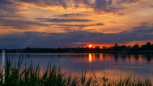 Sonnenuntergang an einem See mit Spiegelung der Sonne