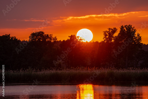 Sonnenuntergang an einem See mit Spiegelung der Sonne