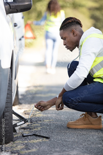 close-up of a worried man looking at punctured car tire