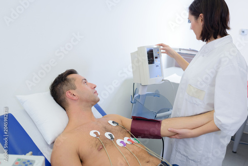 Photos experienced cardiologist attaching sensors to patients chest
