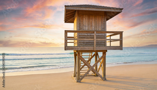 Lifeguard tower on empty beach at colorful sunset
