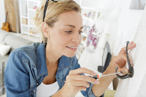 woman mounting coat hook on the wall