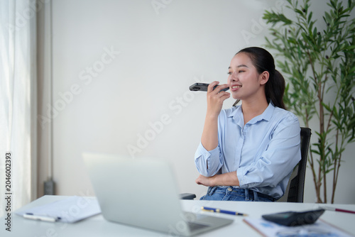 Foto Asian businesswoman communicating using smartphone speakerphone for voice messag