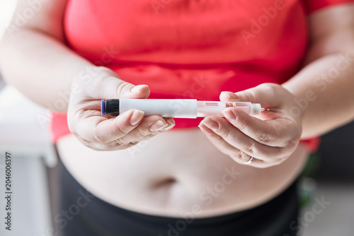 Woman with obesity holding an insulin pump in front of her belly