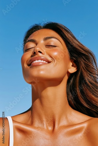 Smiling woman with sun-kissed skin enjoying warm sunlight and relaxed summer feeling outdoors
