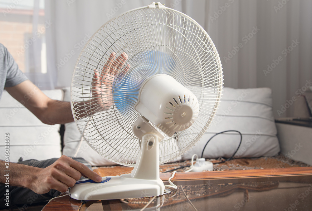 Fototapeta premium Caucasian man with a electric fan at home.
