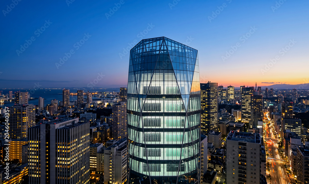 Obraz premium Futuristic glass skyscraper data center in modern city at dusk, urban skyline with server racks visible through illuminated glass facade,