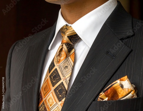 Close-up of a well-dressed individual in a pinstripe suit, crisp white shirt, and patterned tie with a pocket square
