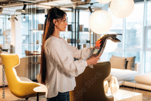 Konstfotografi Female interior designer in white blouse examines color swatches while standing
