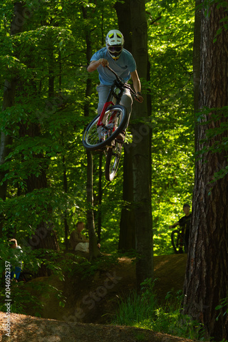 Mountain biker performing a jump on a forest MTB trail | RIder na leśnej trasie MTB
