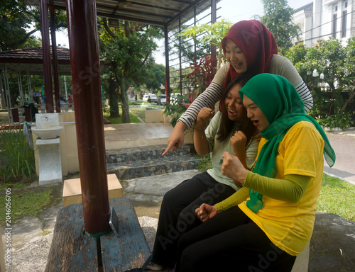 Happy Group Of Asian Women Clenched Fist Celebrates Winning While Watching Football Games On Smartphone At Park