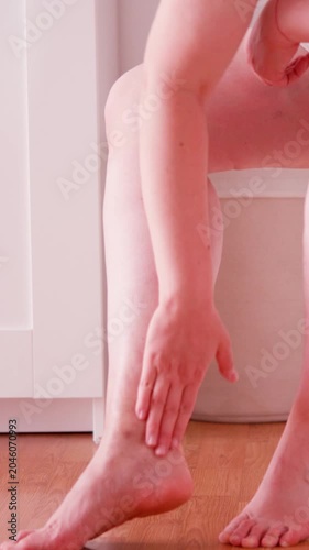 Vertical Close Up of Middle Aged Woman Applying Cream to Leg with Visible Varicose Veins and Spider Veins at Home
