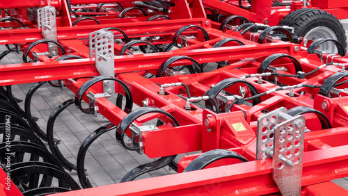 Fotografía Red metal farm implement with multiple wheels, brackets, and curved tines arrang