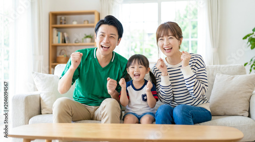 テレビでスポーツ観戦をしてリビングで熱狂しながら応援する笑顔の家族