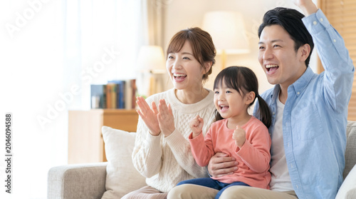 テレビでスポーツ観戦をしてリビングで熱狂しながら応援する笑顔の家族