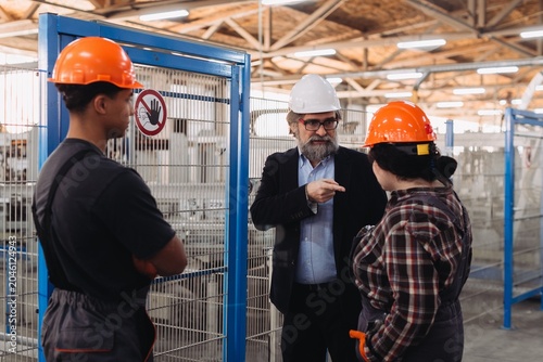 Photos Manager instructing industrial workers during factory discussion