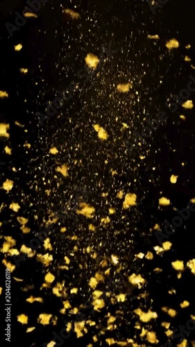 Falling golden confetti and glitter dust on black background
