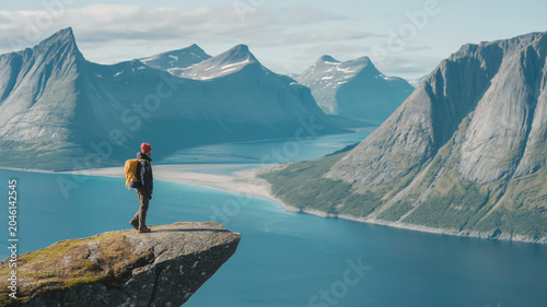 Solo hiker conquering mountain heights overlooking a serene fjord