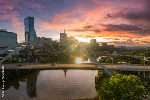Korean Veterans Memorial Bridge in Nashville city, Tennessee, USA. Highway traffic driving cars in downtown district. American city skyline with brightly illuminated buildings at sunset.