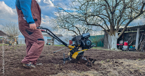 фотографія Man operating a walk-behind tractor, tilling and cultivating spring garden soil