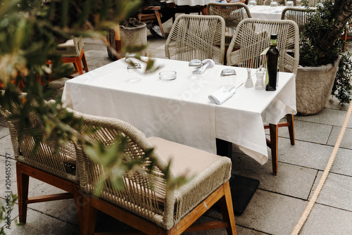 Stylish restaurant terrace with neatly arranged tables and woven chairs. Hospitality, dining and leisure concept.
