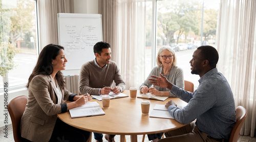 group mentorship coaching diverse team meeting guidance leadership support learning small circle listens to experienced mentor during bright collaborative session around table with notebooks for
