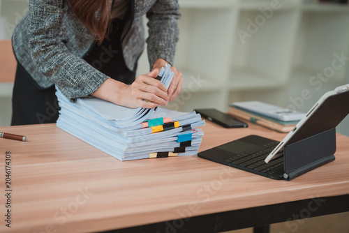 Schilderij op canvas A close-up image of a businesswoman's hands rummaging through a large stack of documents on her desk, organizing papers and files in her office using a digital tablet