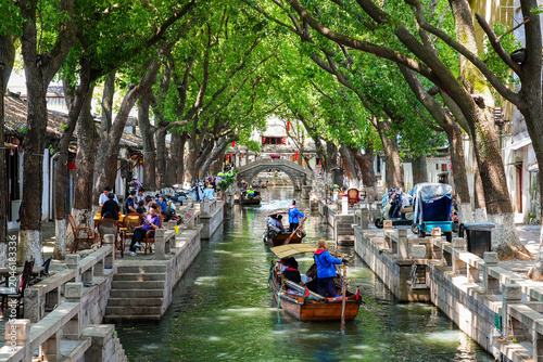 Foto Traditional wooden tourist boats navigating a scenic canal in Tongli water town,