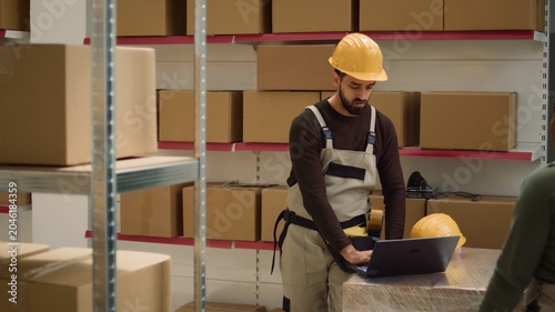 Photos Tracking shot of warehouse chief operations officers inputing updated products i