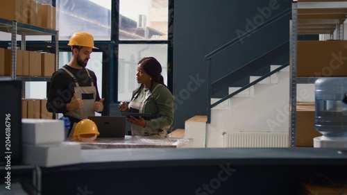 Photos Dolly out shot of employees doing warehouse inventory analysis, keeping quality standards high