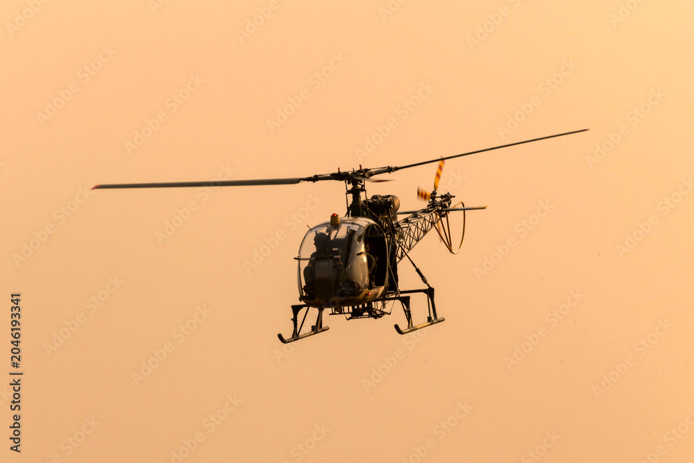 Fototapeta premium Silhouette helicopter flying towards me on isolated sky during dawn
