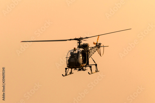 Silhouette helicopter flying towards me on isolated sky during dawn