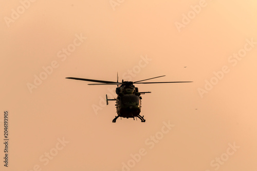 Silhouette helicopter flying towards me on isolated sky during dawn