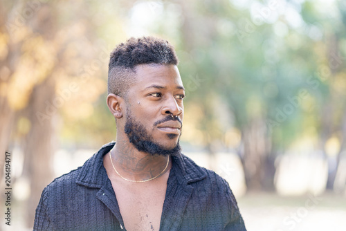 Stylish Black Man with Beard and Piercings Outdoors in Soft Sunlight