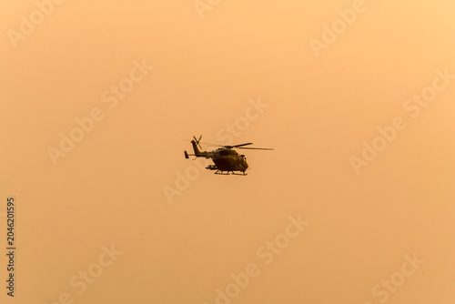 Silhouette helicopter flying towards me on isolated sky during dawn