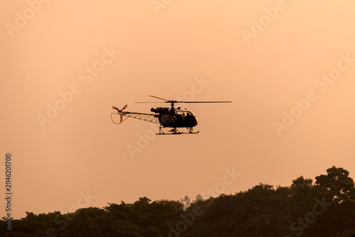 Silhouette helicopter flying towards me on isolated sky during dawn