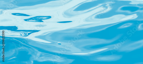 Fotografie Close-up of blue water surface with subtle ripples and reflections, capturing a