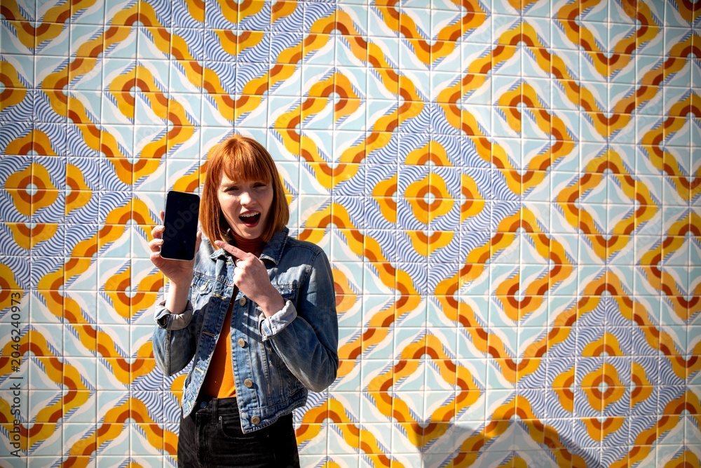 Obraz premium Excited woman showcasing smartphone outdoors.