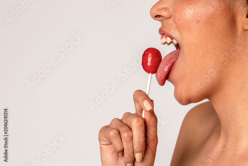 Tableau sur toile Close-up of a person licking a red lollipop against a plain background