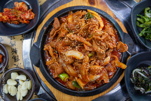Spicy stir fried pork with onions and green onions served on a sizzling hot plate, traditional Korean dish featuring rich red pepper seasoning and savory flavor.