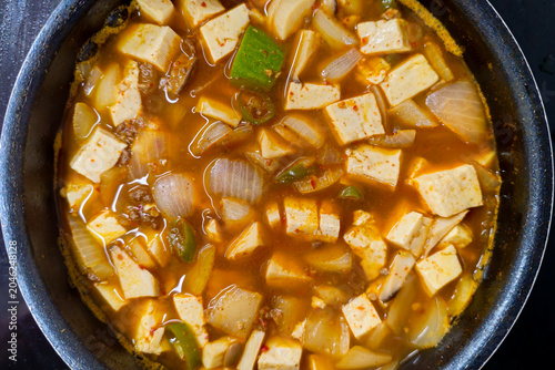 Traditional Korean soybean paste stew with tofu onions mushrooms and green chili peppers simmering in a pot, showcasing authentic Korean home cooking and healthy comfort food.