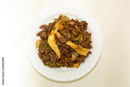 Korean beef bulgogi stir fried with mushrooms, onions, and green onions, featuring savory soy sauce seasoning and authentic Korean cuisine on a white plate.